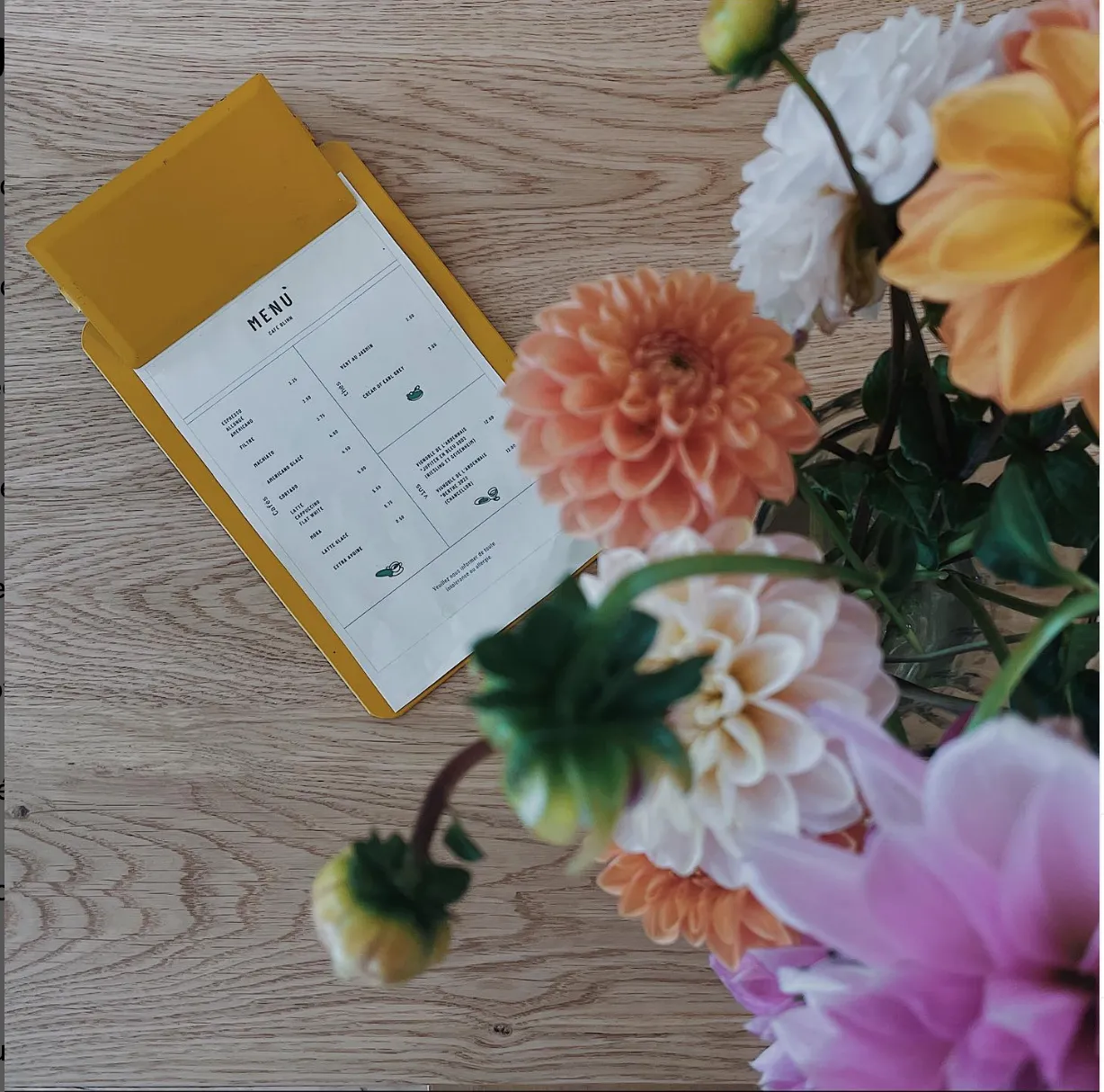 Bouquet de fleurs colorées à côté d’un menu posé sur une table en bois
